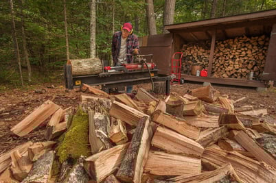 A man uses firewood processing tools to cut logs.